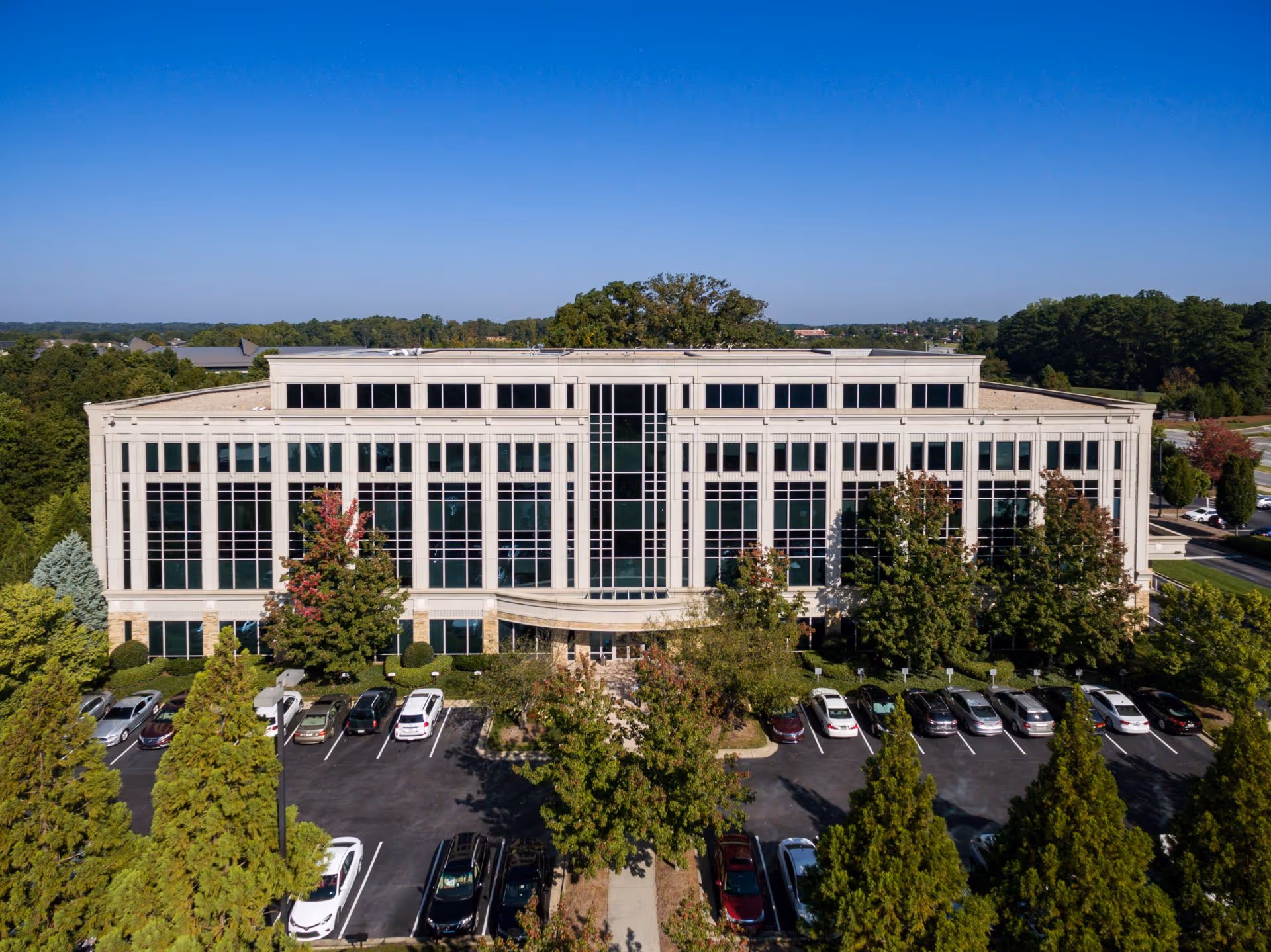 Aerial view of a large glass-front building with a parking lot.