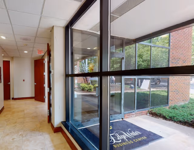 Bright corridor inside a senior living facility with large windows and hallway doors.