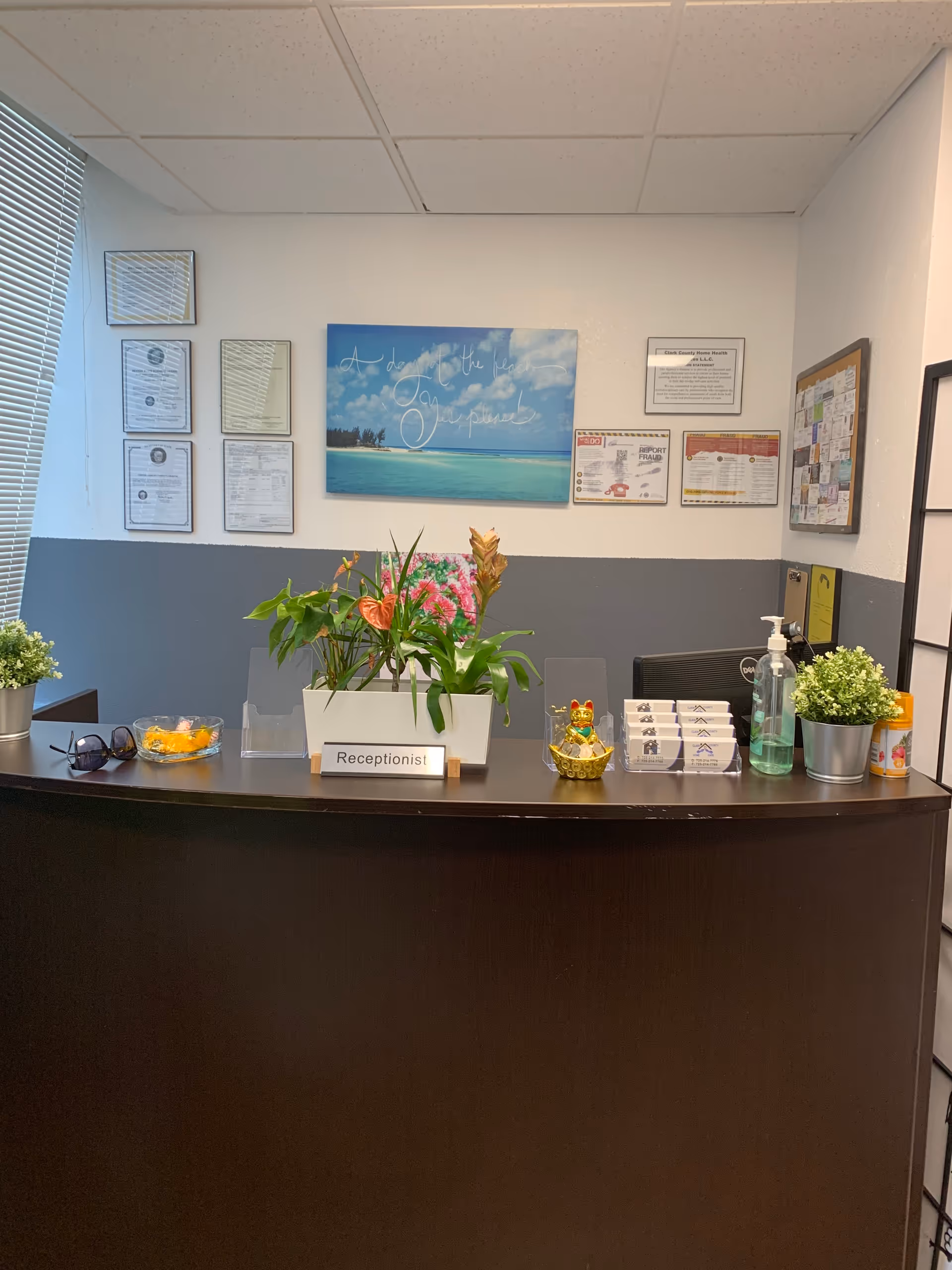Reception desk with plants, brochures, and sanitizer in a senior care facility lobby.