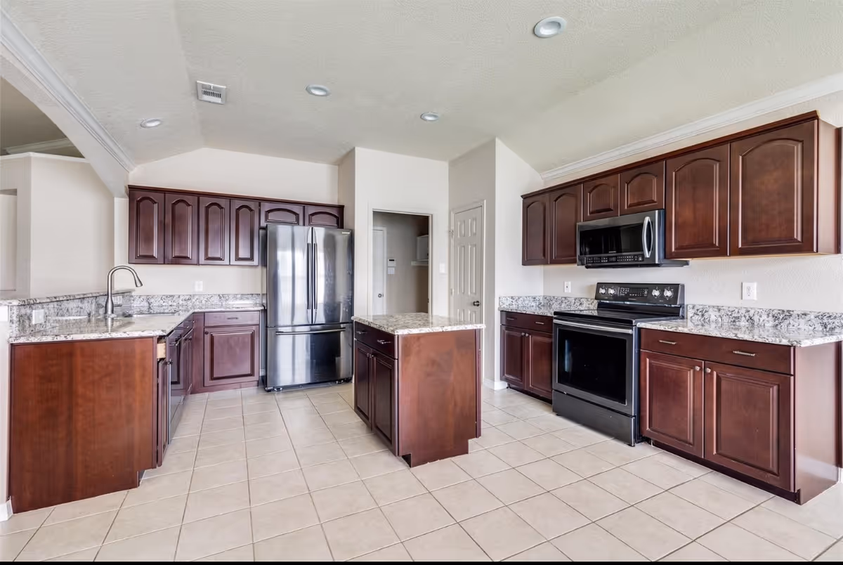 Modern kitchen with dark wood cabinets, stainless appliances, and a central island.