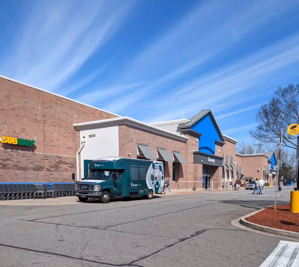 Brick storefront building with Subway sign, blue roof accents, and a service van.