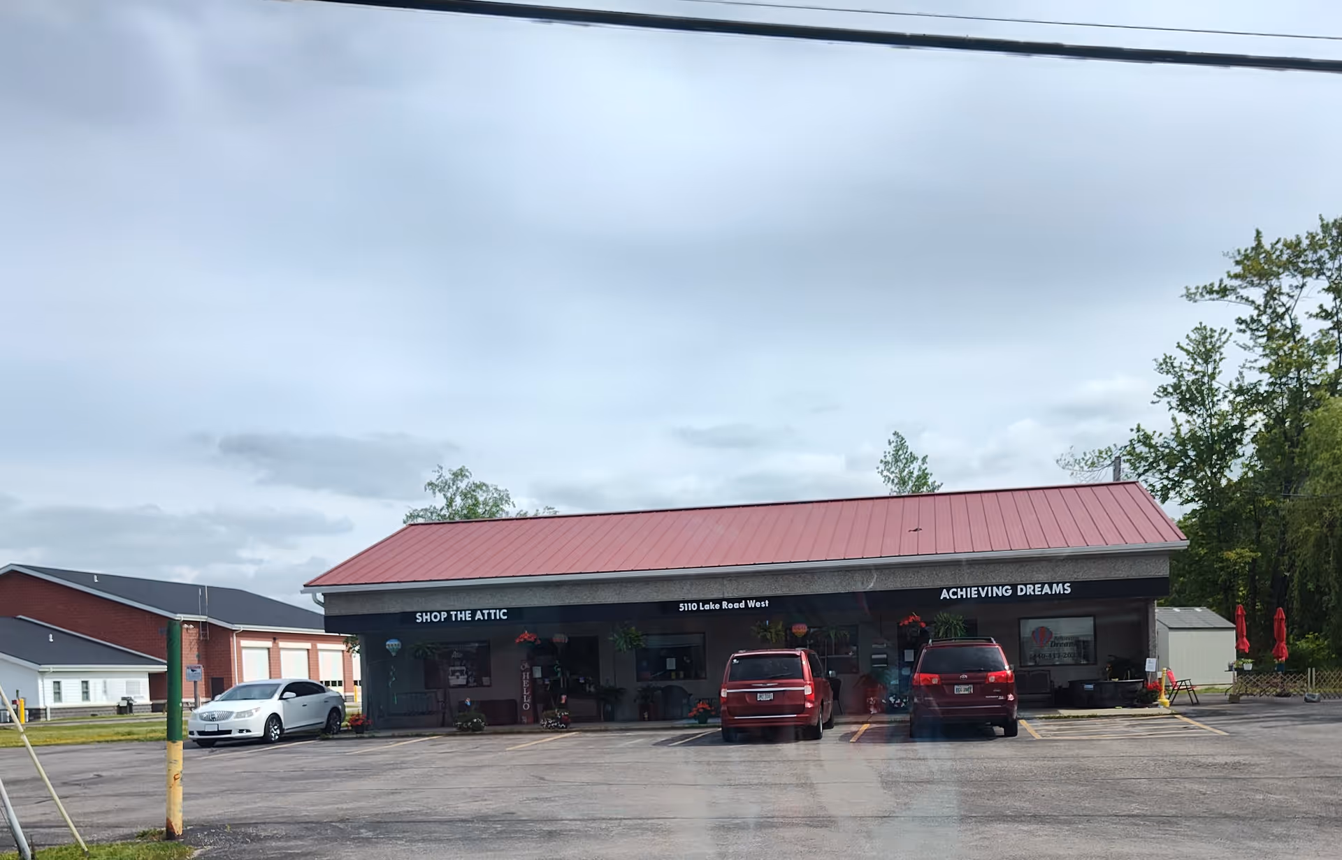 Single-story storefront with red roof, Achieving Dreams signage, and a parking lot.
