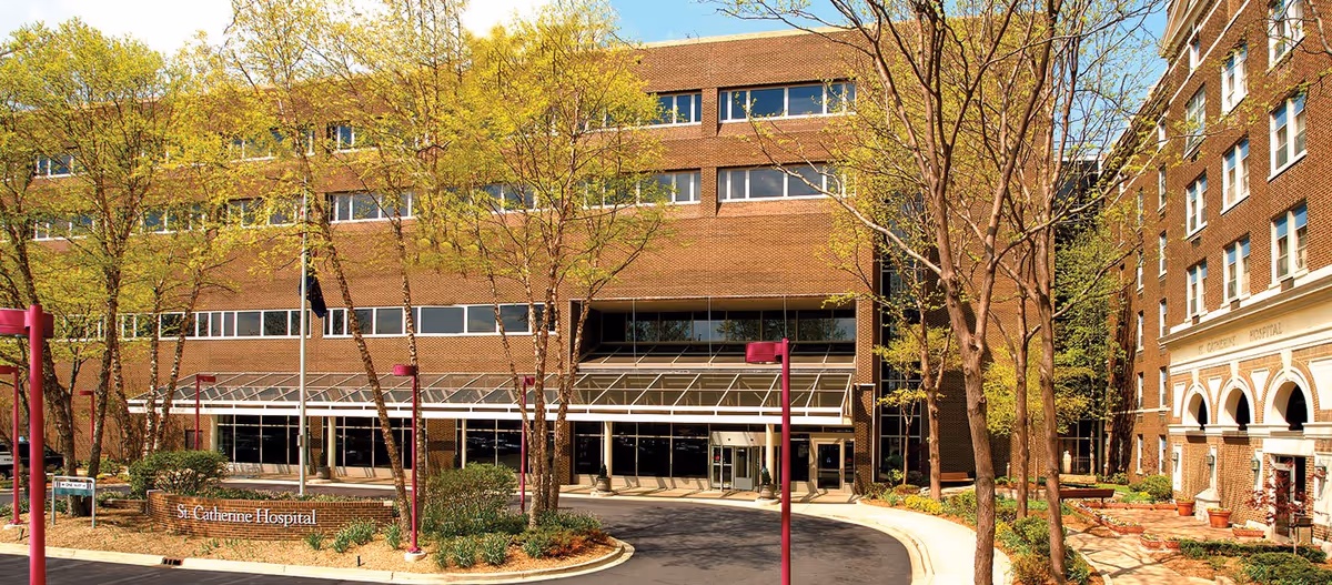 Exterior view of St. Catherine Hospital entrance with trees and brick facade.