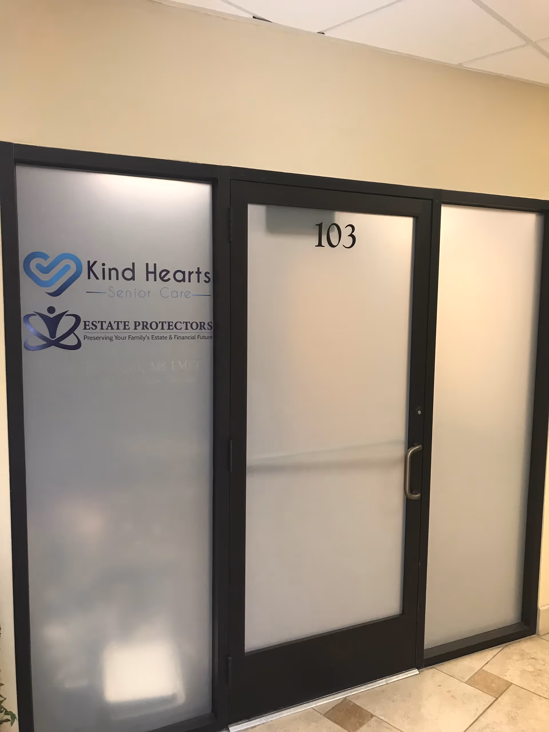 Frosted glass doors with Kind Hearts Senior Care logo and room number 103 in a hallway.