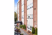 Exterior view of a multi-story brick senior living facility with windows and landscaping.