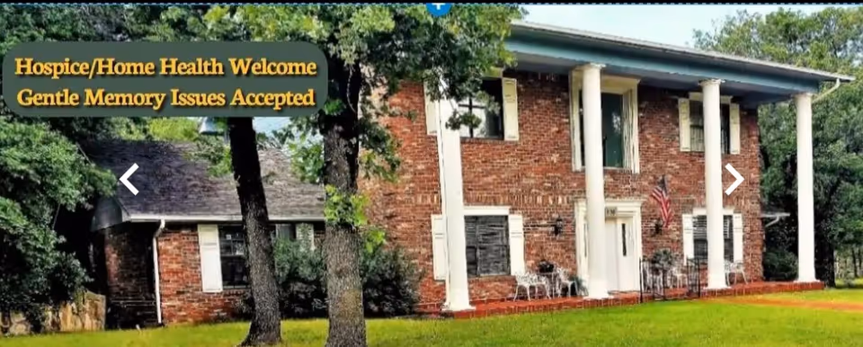 Brick two-story building with white columns and a front porch, surrounded by trees