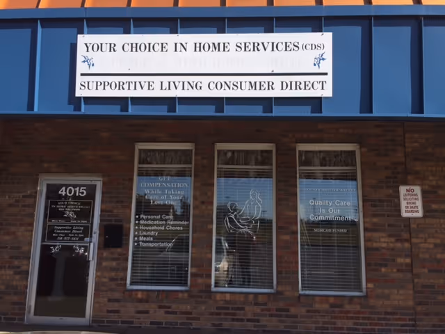 A brick building front features a blue awning and a sign reading Supportive Living Consumer Direct.