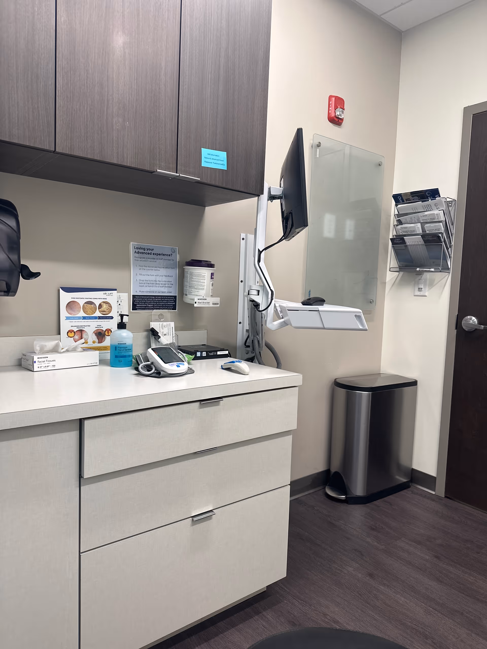 Clinic-like examination area with cabinets, monitor, and medical supplies.