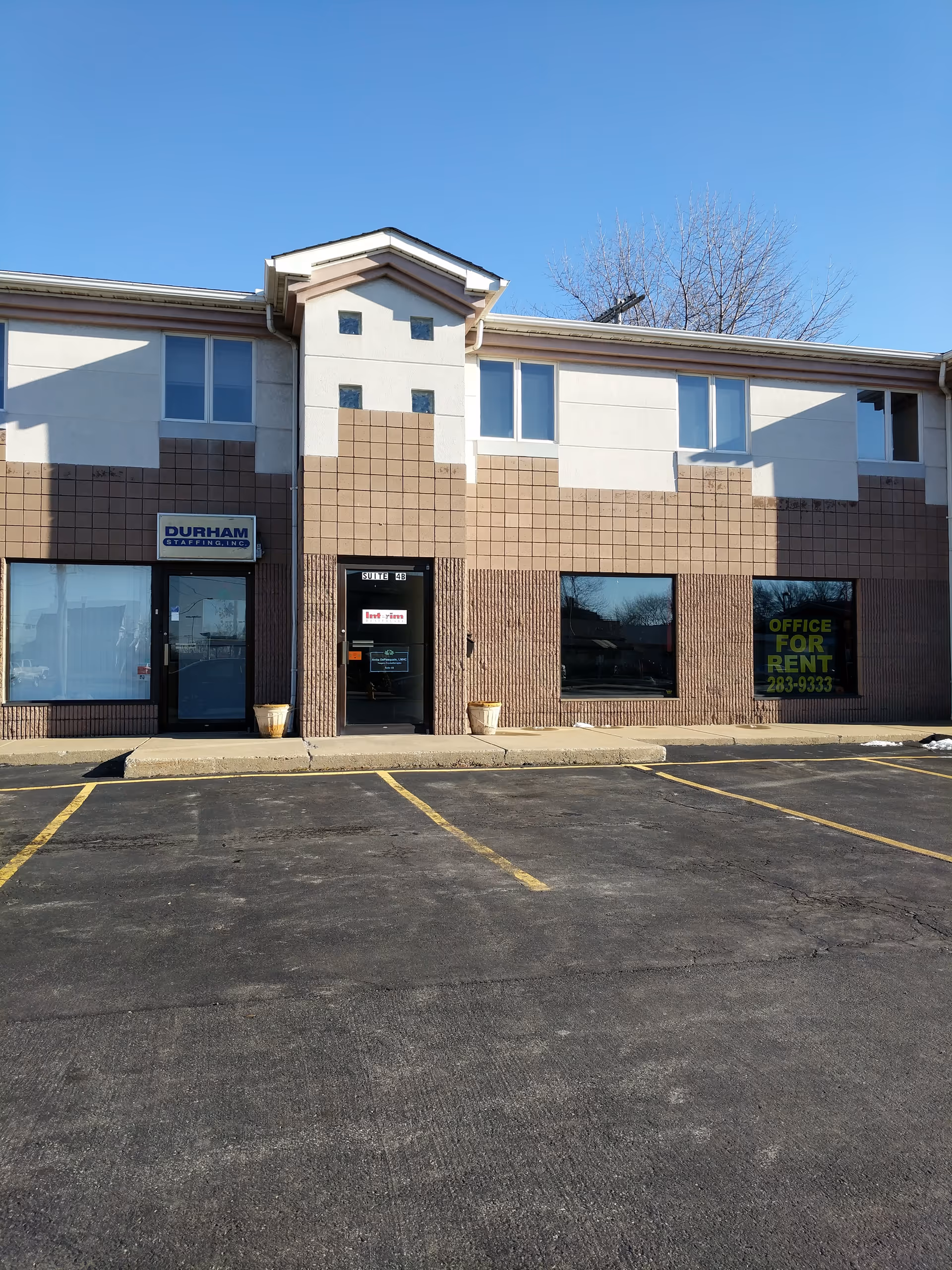 Front view of a two-story commercial building with parking and storefront windows.