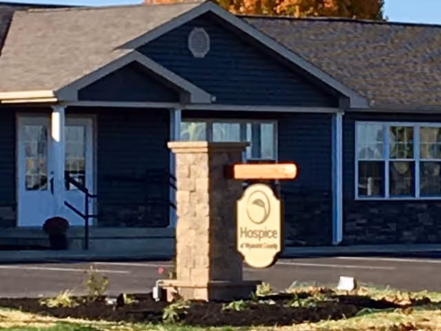 Blue building exterior with a stone sign pillar and Hospice Wyandot Memorial sign in front