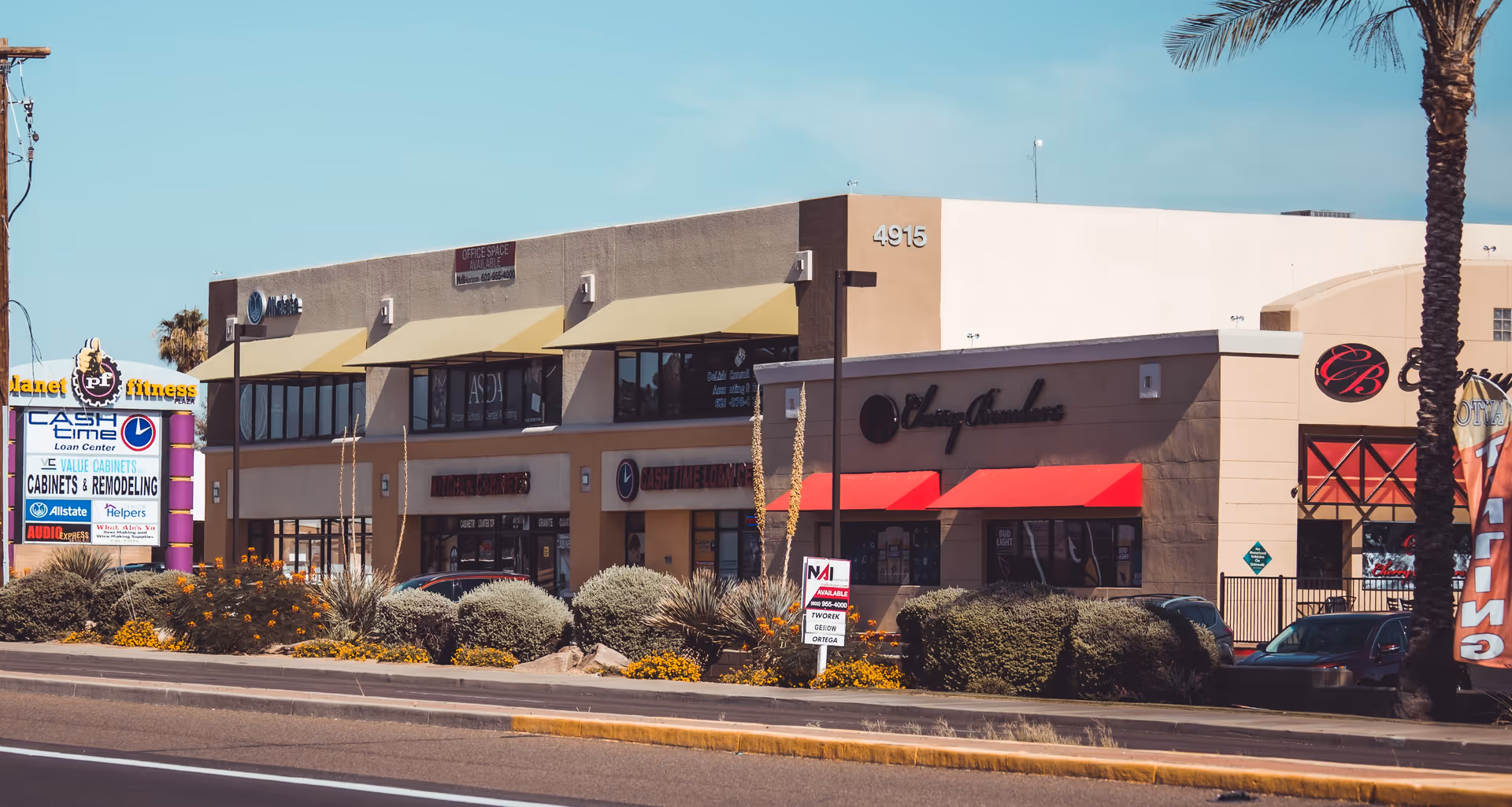 Exterior view of a strip mall with storefronts and desert landscaping