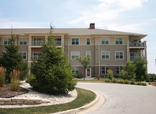 Multi-story senior living building with landscaped entrance and curved driveway.