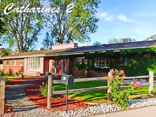 Front exterior of a single-story red brick senior living home with greenery.