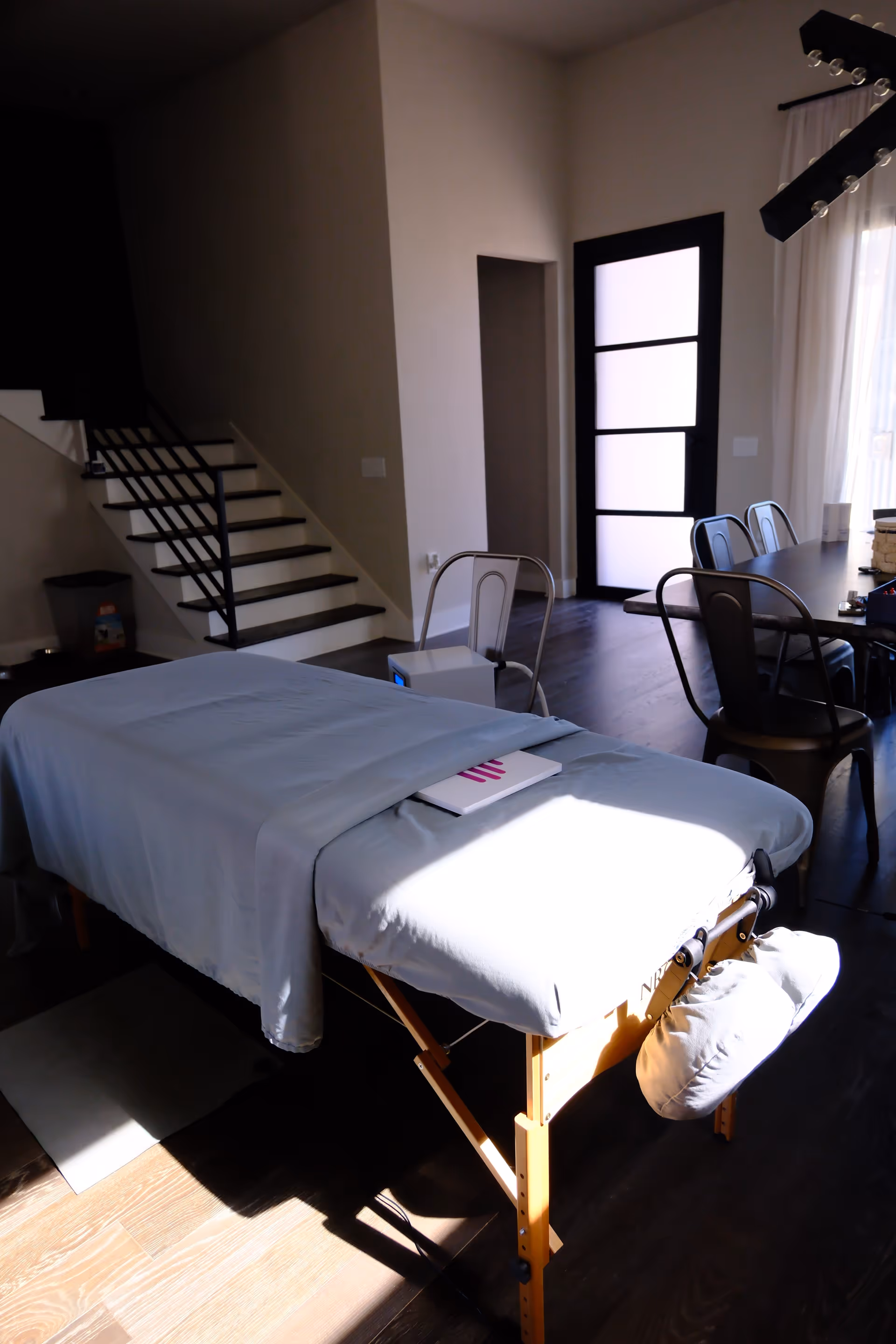 Massage table with a light blue sheet sits in a bright, modern interior.