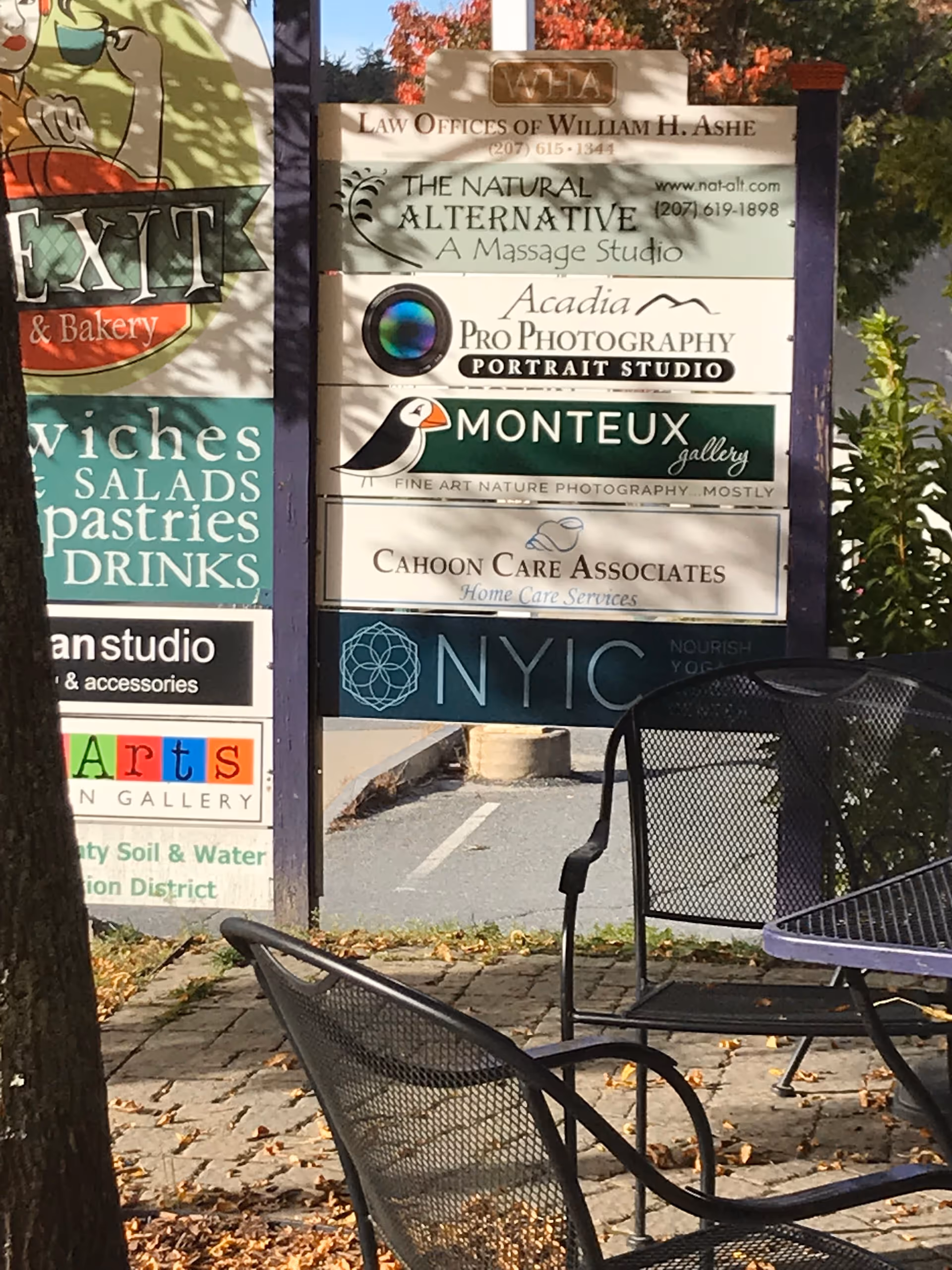 Outdoor seating area with a tall signboard listing Cahoon Care Associates among other businesses.