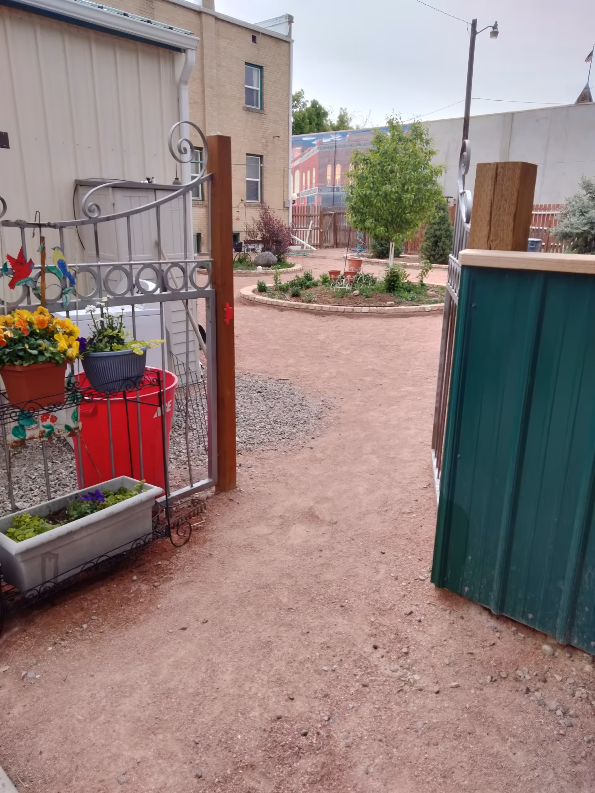 Gated outdoor courtyard at Delta House with potted plants and a dirt path.