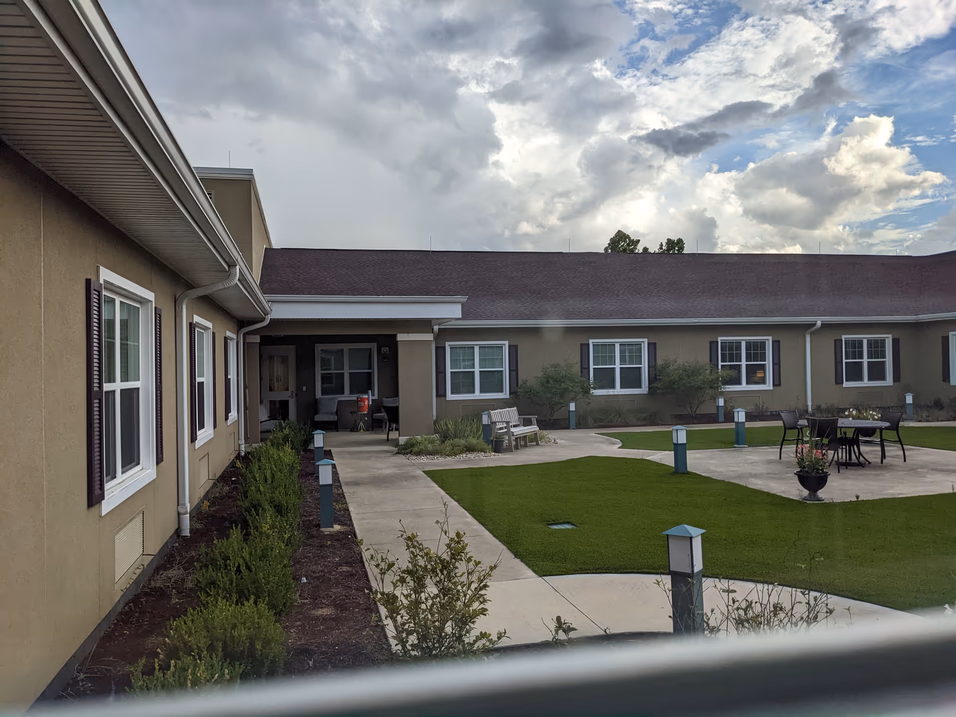 Exterior view of De Luna Health and Rehabilitation Center courtyard with lawns, benches and outdoor furniture.