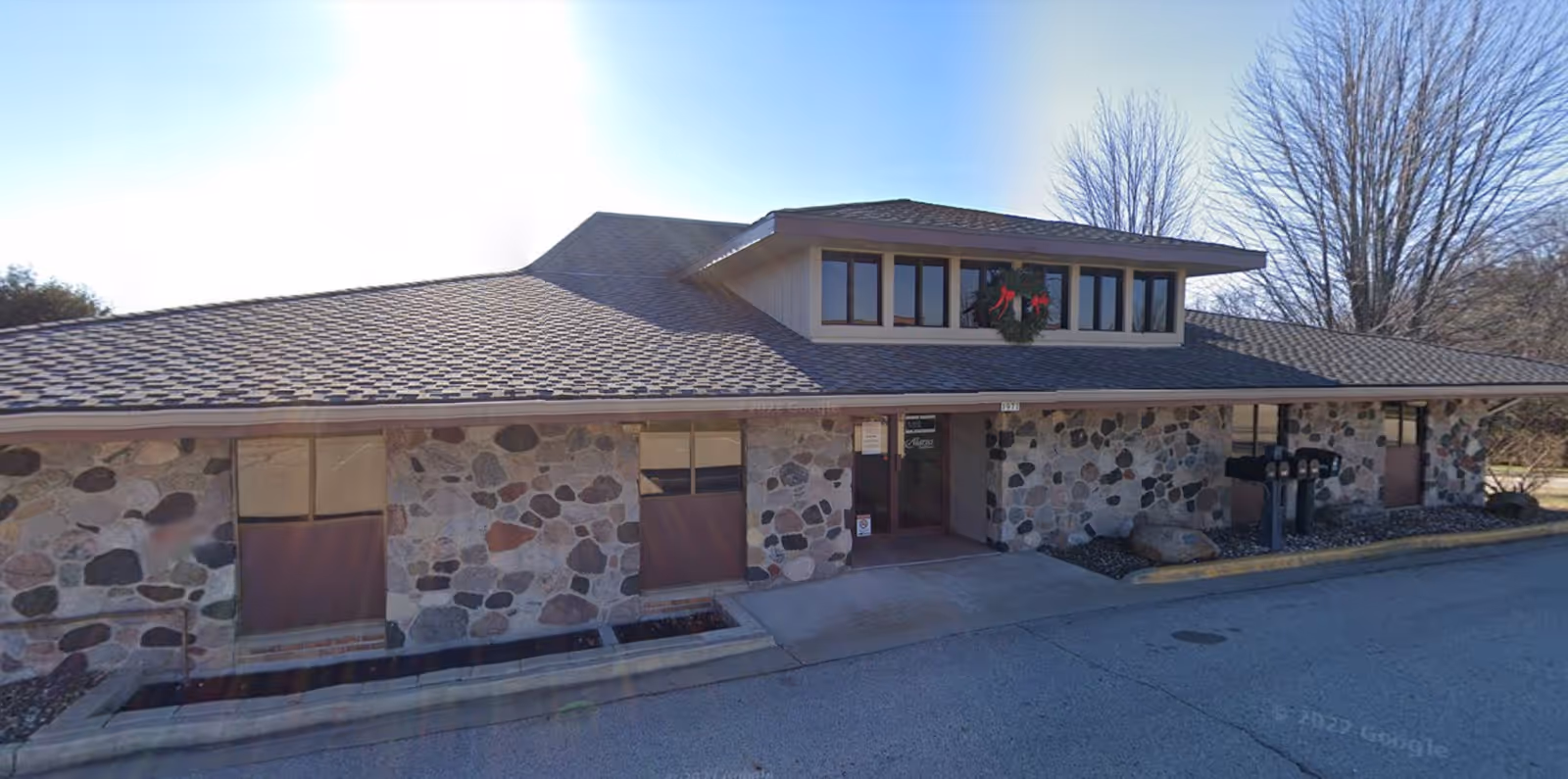 Exterior view of a stone-faced senior living facility with a wreath and front driveway.