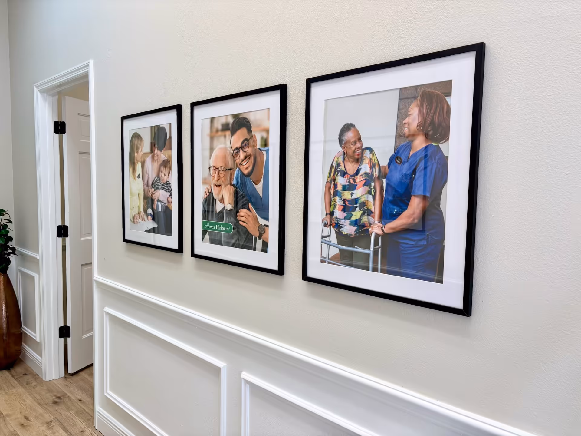 Hallway with three framed photos along a wainscoted wall in a senior living facility