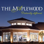 Exterior view of The Maplewood Nursing Home building at dusk, showing a well-lit entrance with large windows and a distinctive roof design.