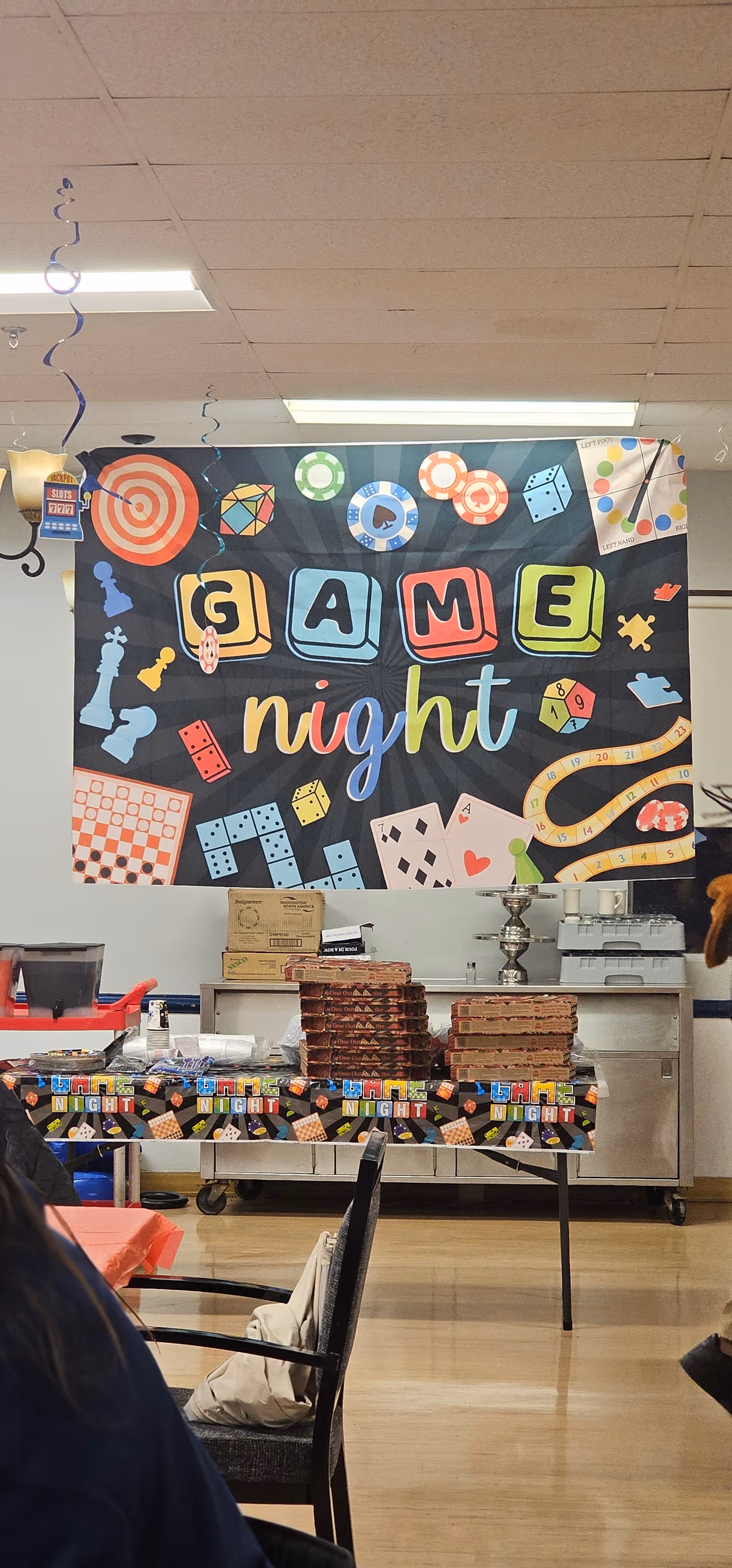 Indoor facility room with a colorful GAME night banner and tables arranged for activities.