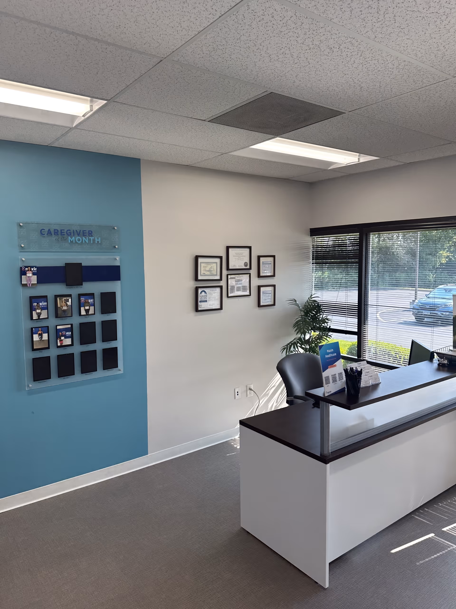 Reception desk in a bright lobby with blue accent wall and framed certificates.