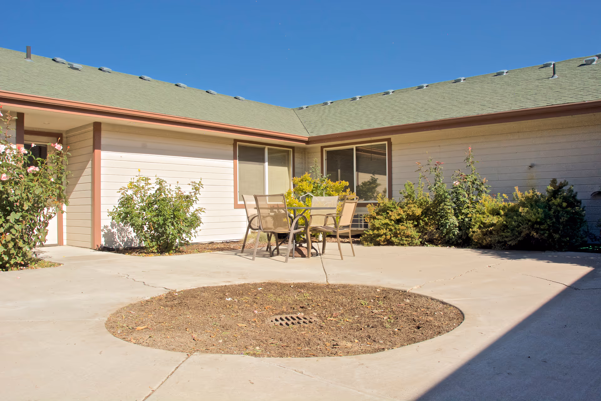 Exterior view of Brookdale Chubbuck courtyard with a seating table and shrubs.