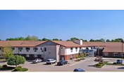 Exterior view of Senior Suites of Urbandale, a low rise senior living building with cars parked.