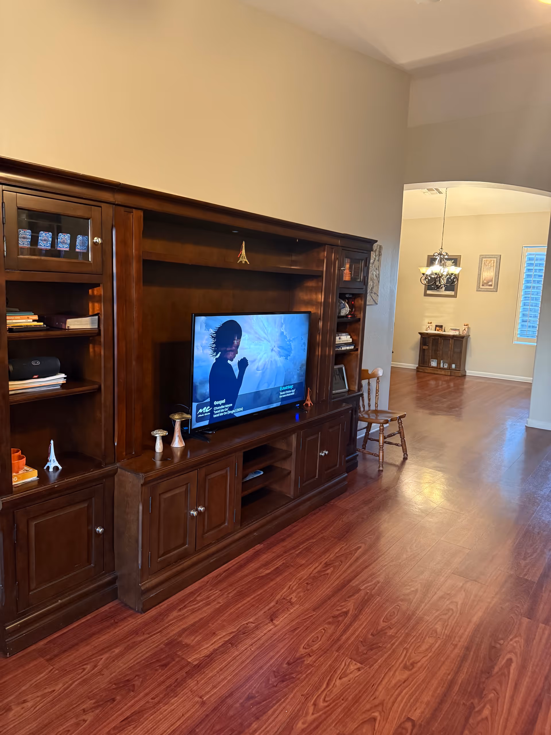 Dark wooden entertainment center with TV and shelves in a living room.