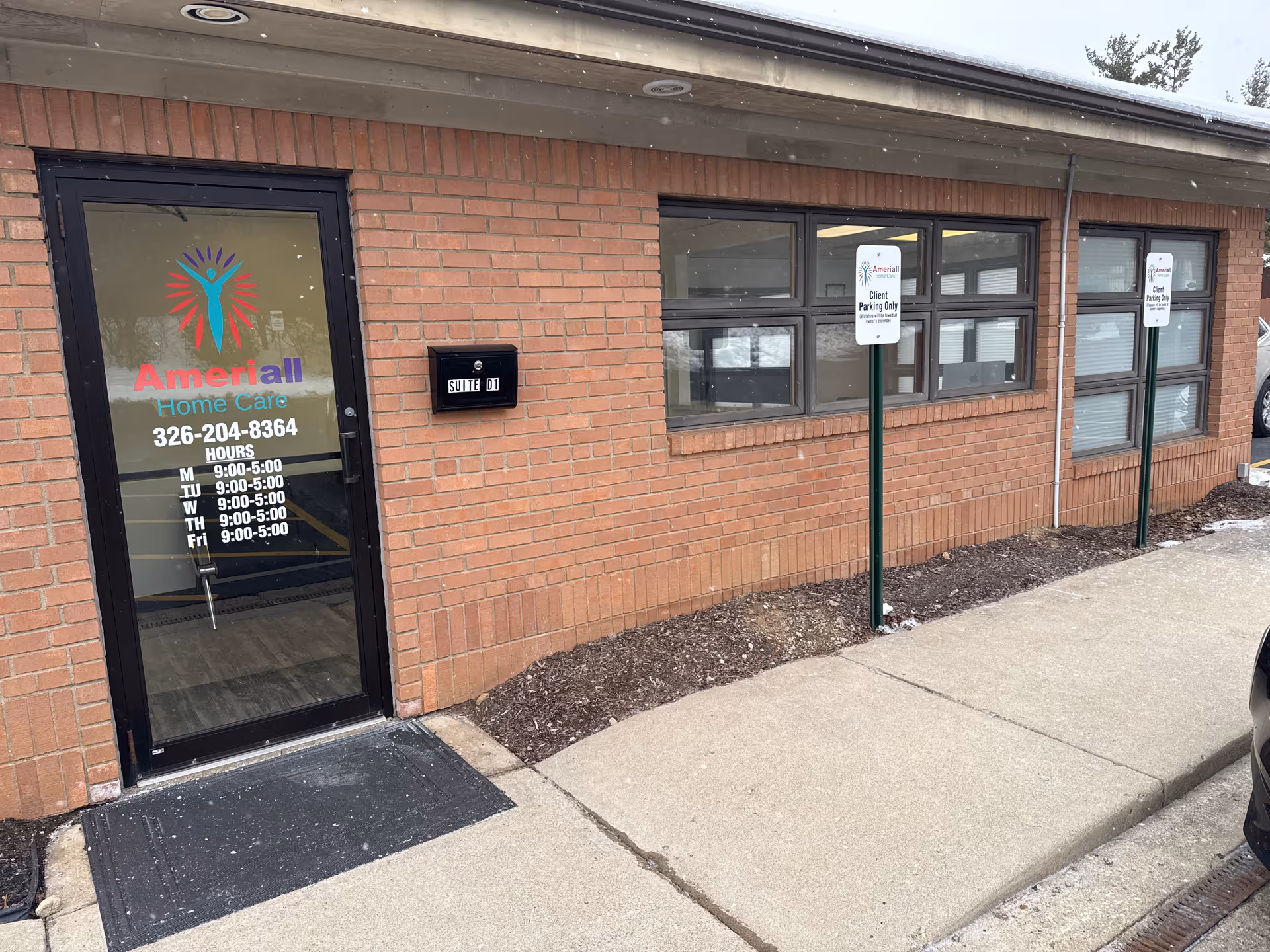 Brick exterior of Ameriall Home Care LLC building with entrance door and parking signs.