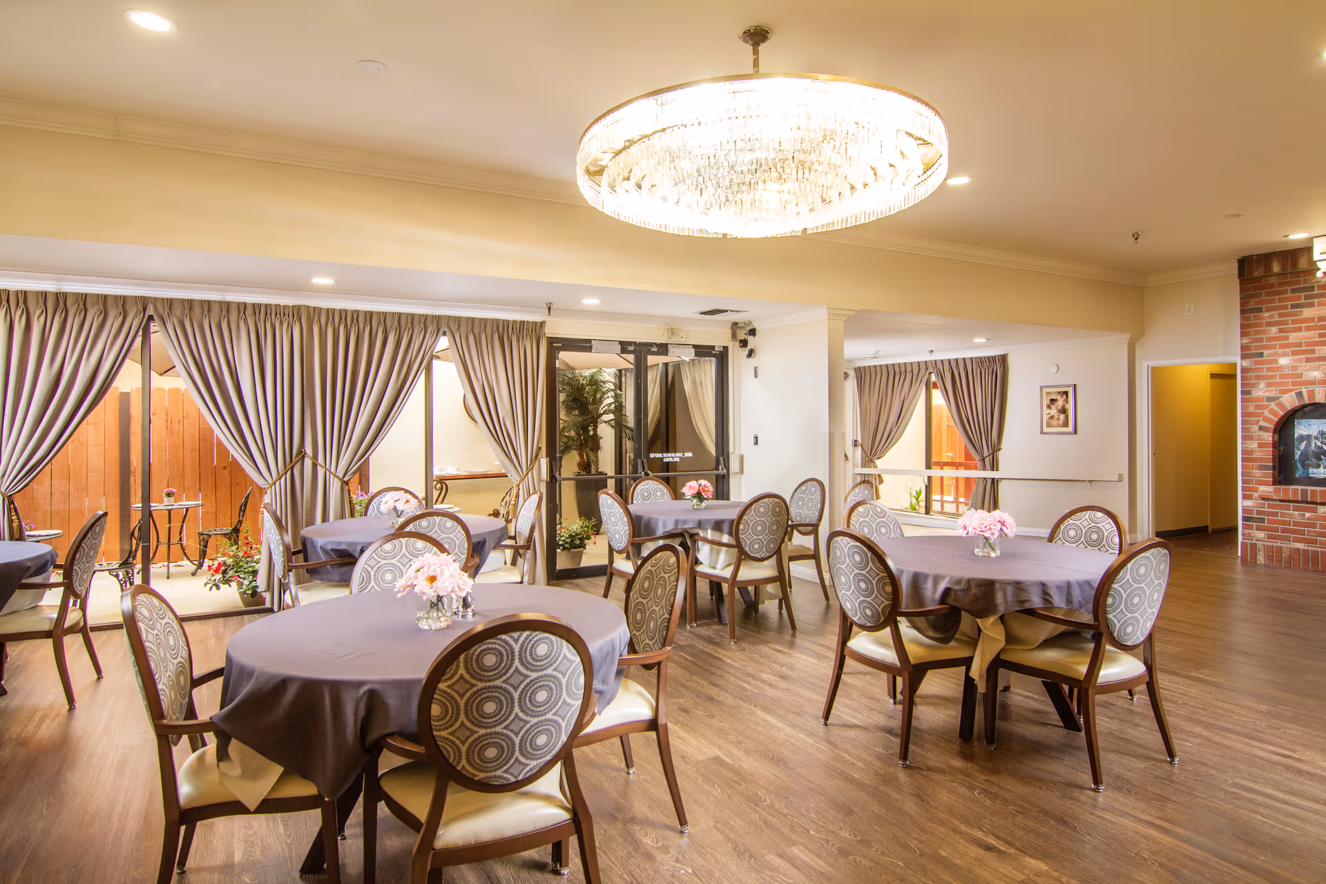 A formal dining area with round tables, purple tablecloths, and a chandelier.