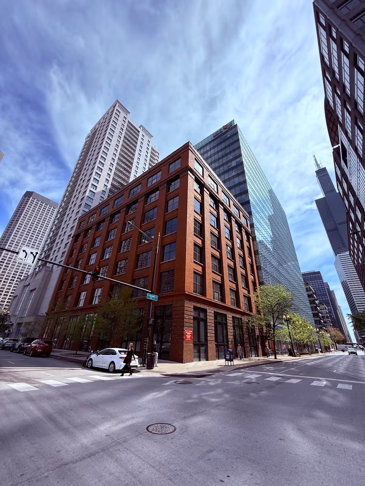 Urban street scene with a red brick building and surrounding high-rise towers.