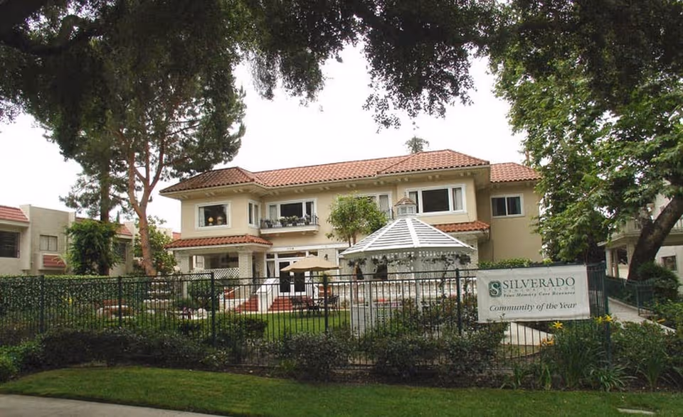 Two-story Silverado memory care building with a courtyard, gazebo, and manicured landscaping.