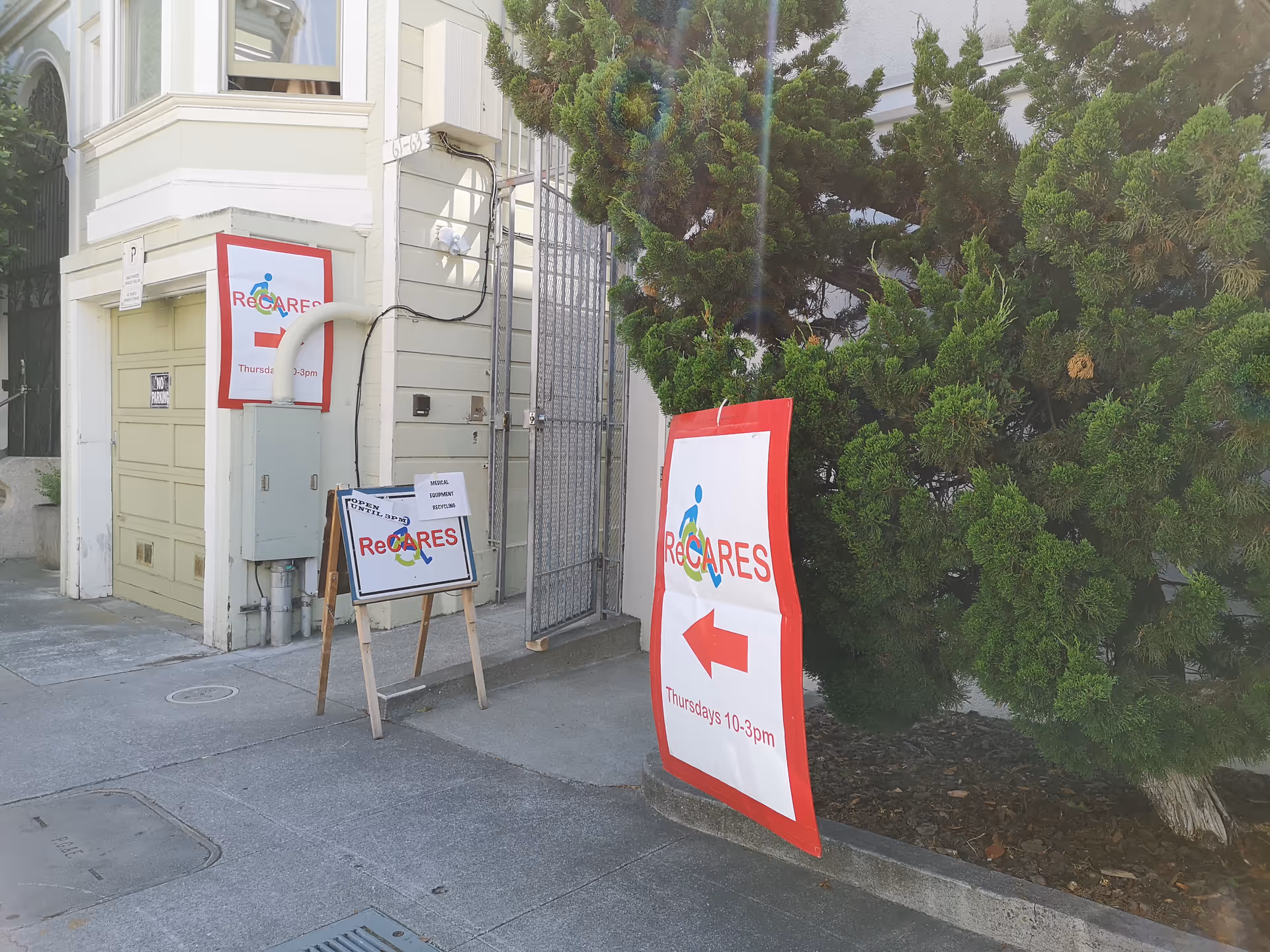 Exterior of ReCARES facility showing entrance gate and signage beside sidewalk.