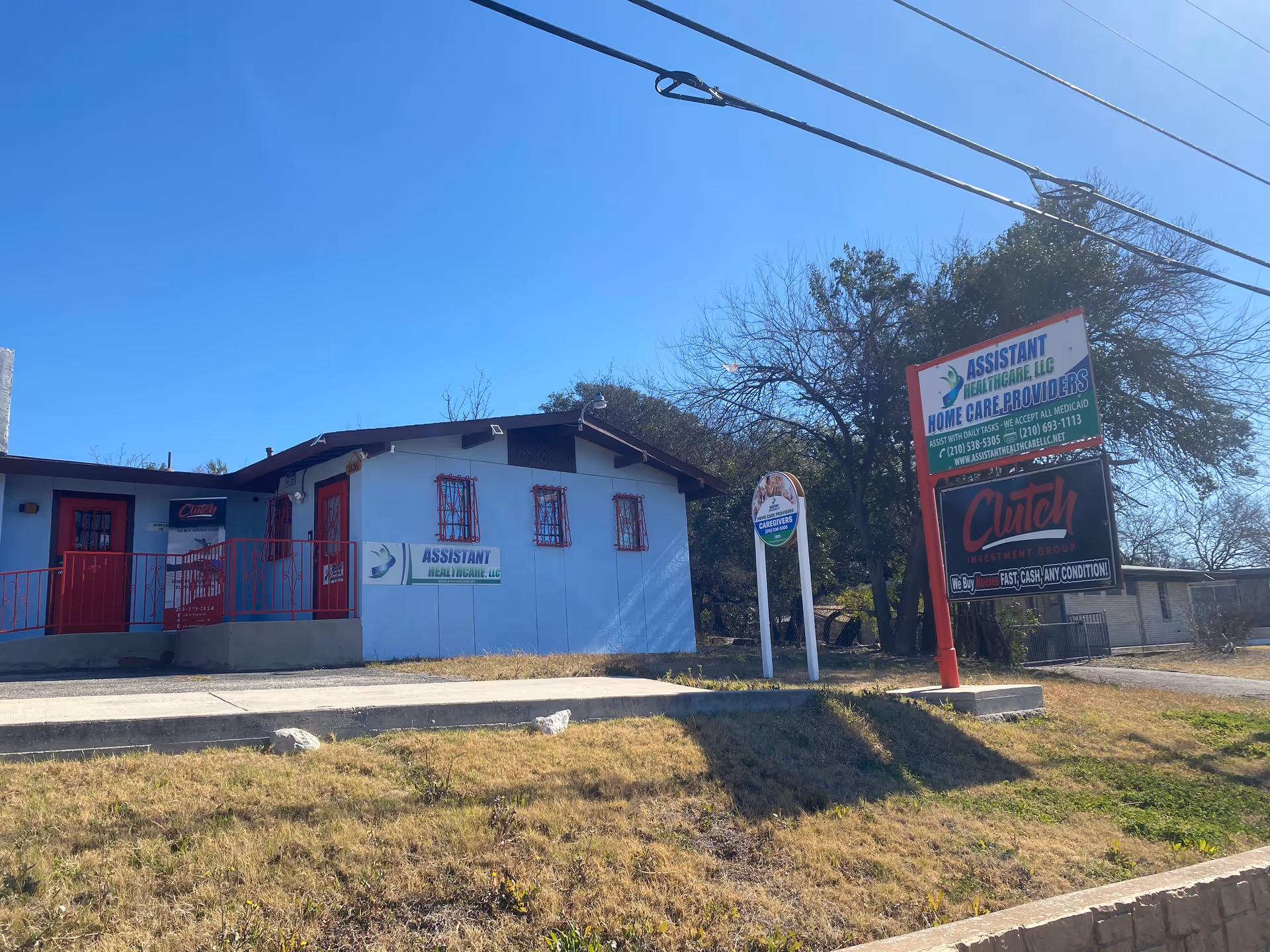 Blue single-story building with red railings and signs advertising Assistant Healthcare LLC.
