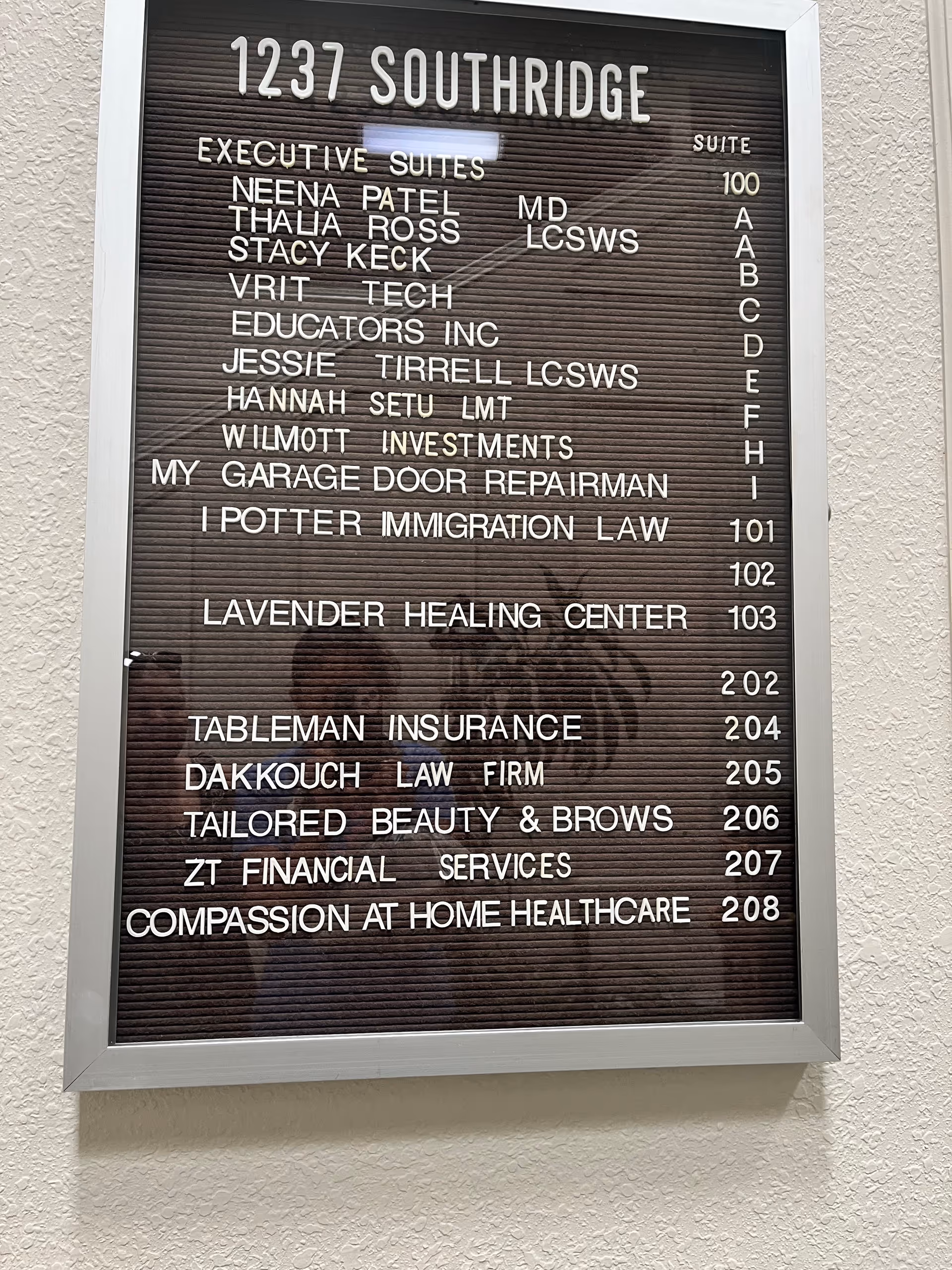Wall-mounted directory board listing suites and business names, including Compassion at Home Healthcare.
