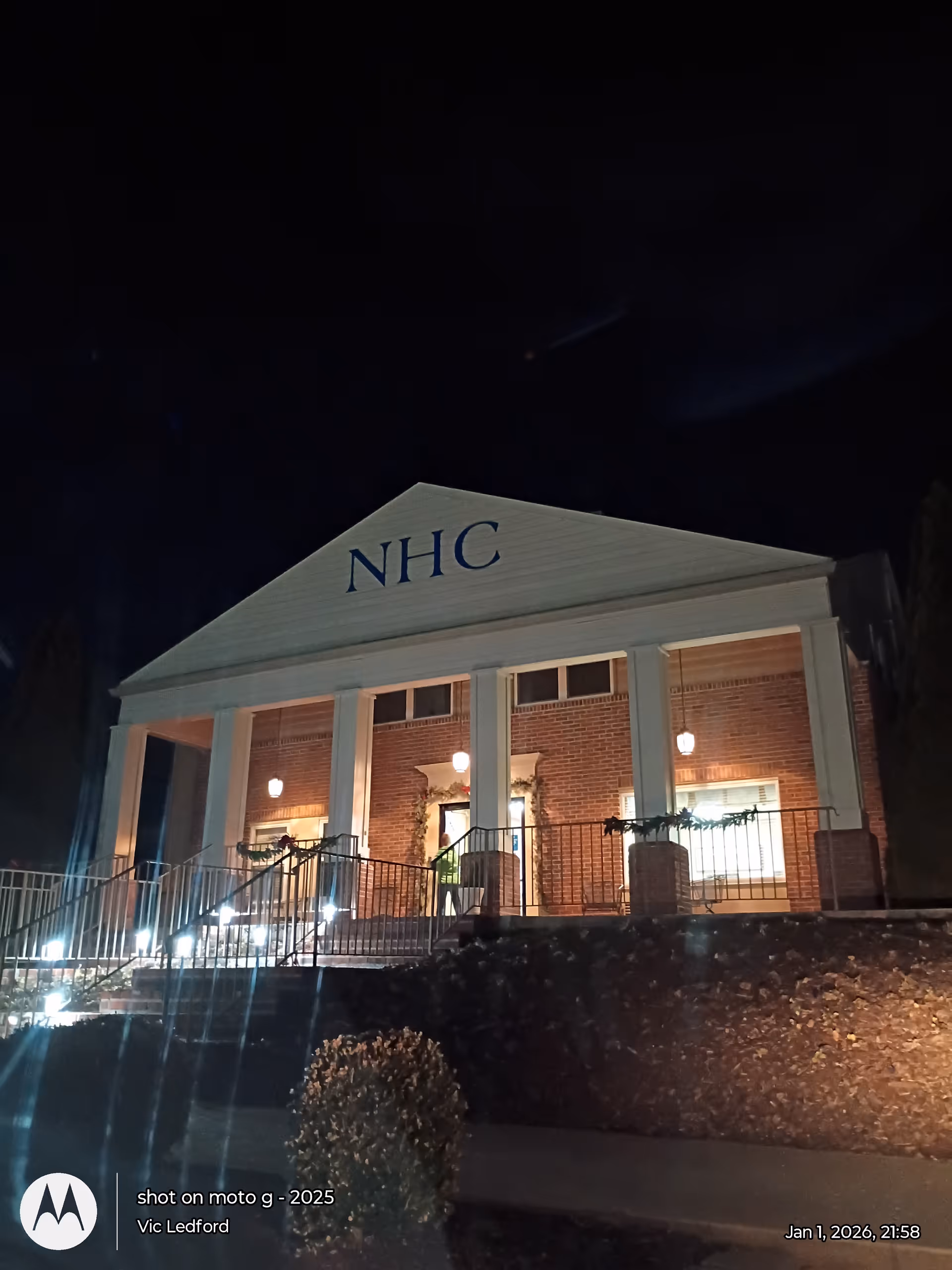 NHC Healthcare Johnson City building at night with brick facade, columns, and entrance lights.