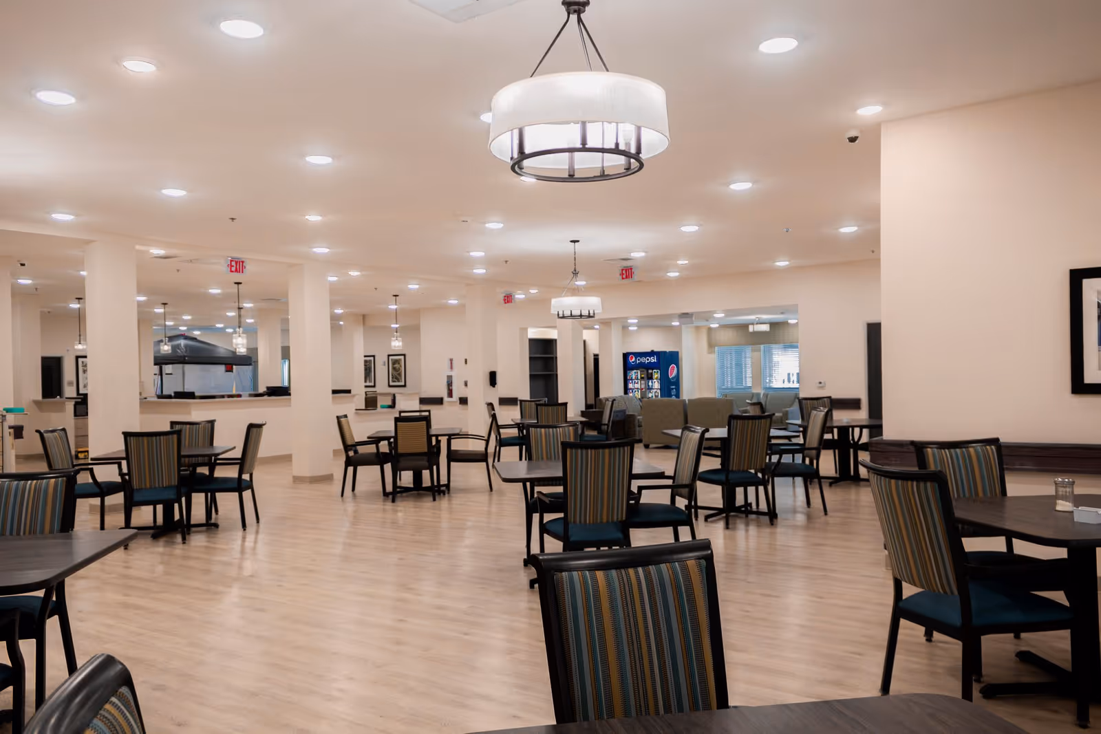 Interior of a senior living facility dining area with many tables and chairs.