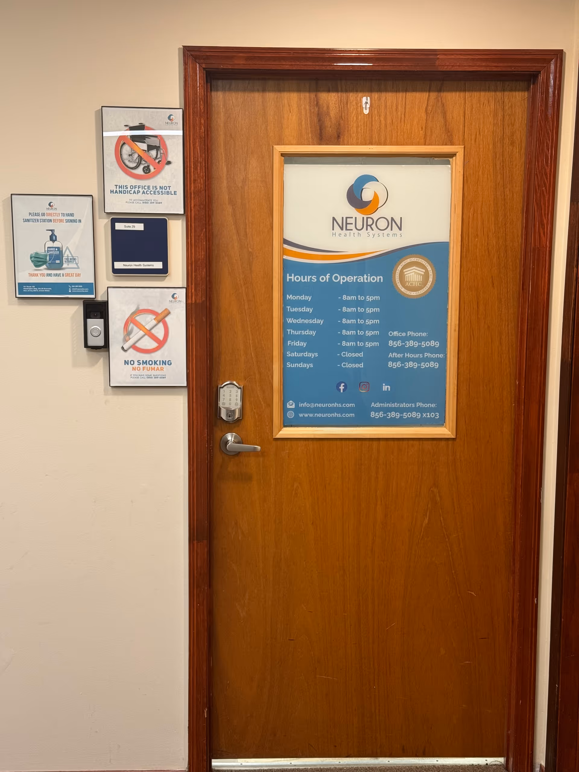 Wooden door with Neuron Health Systems sign and hours posted in an interior hallway