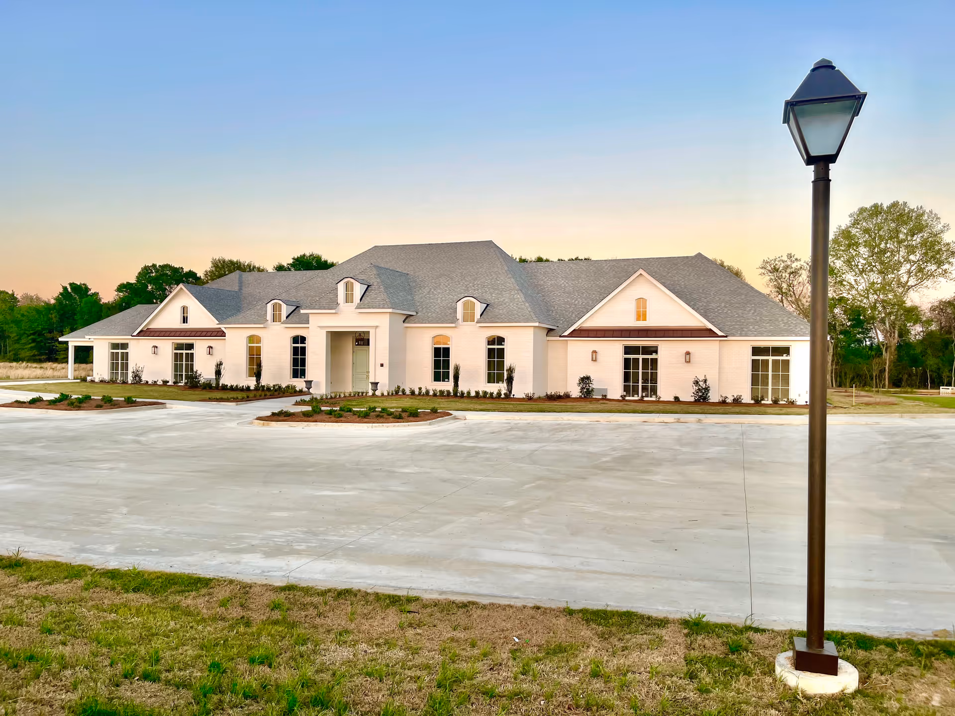 White, single-story senior living facility with a gabled roof and a lamp post in foreground