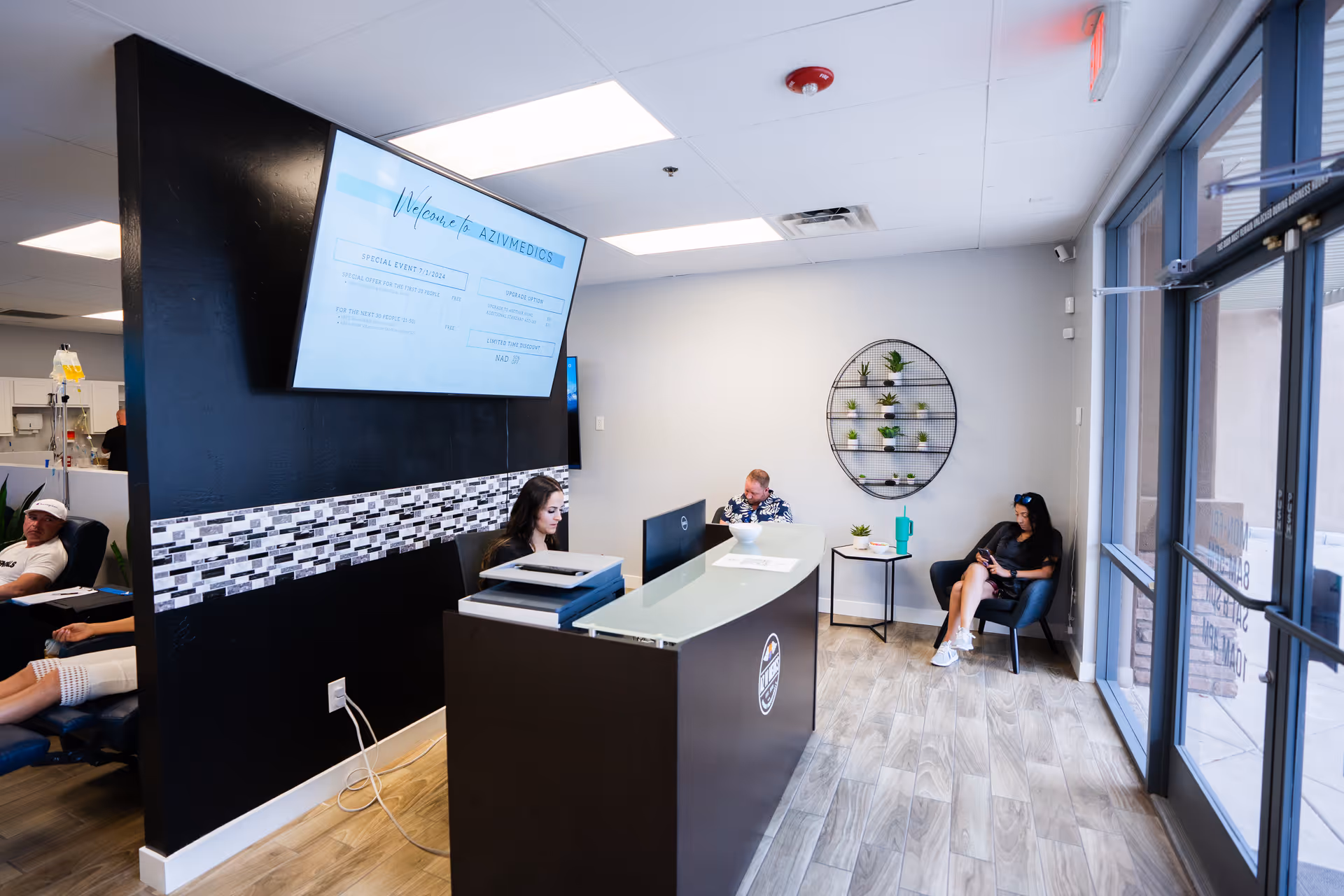 Reception area of AZ IV Medics with a dark front desk, seating, and a large monitor.
