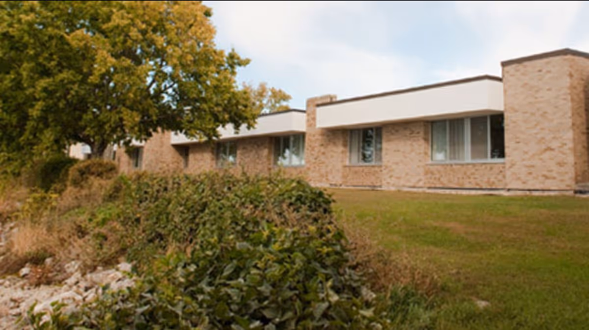 Exterior view of a brick senior living facility with windows and surrounding landscaping.