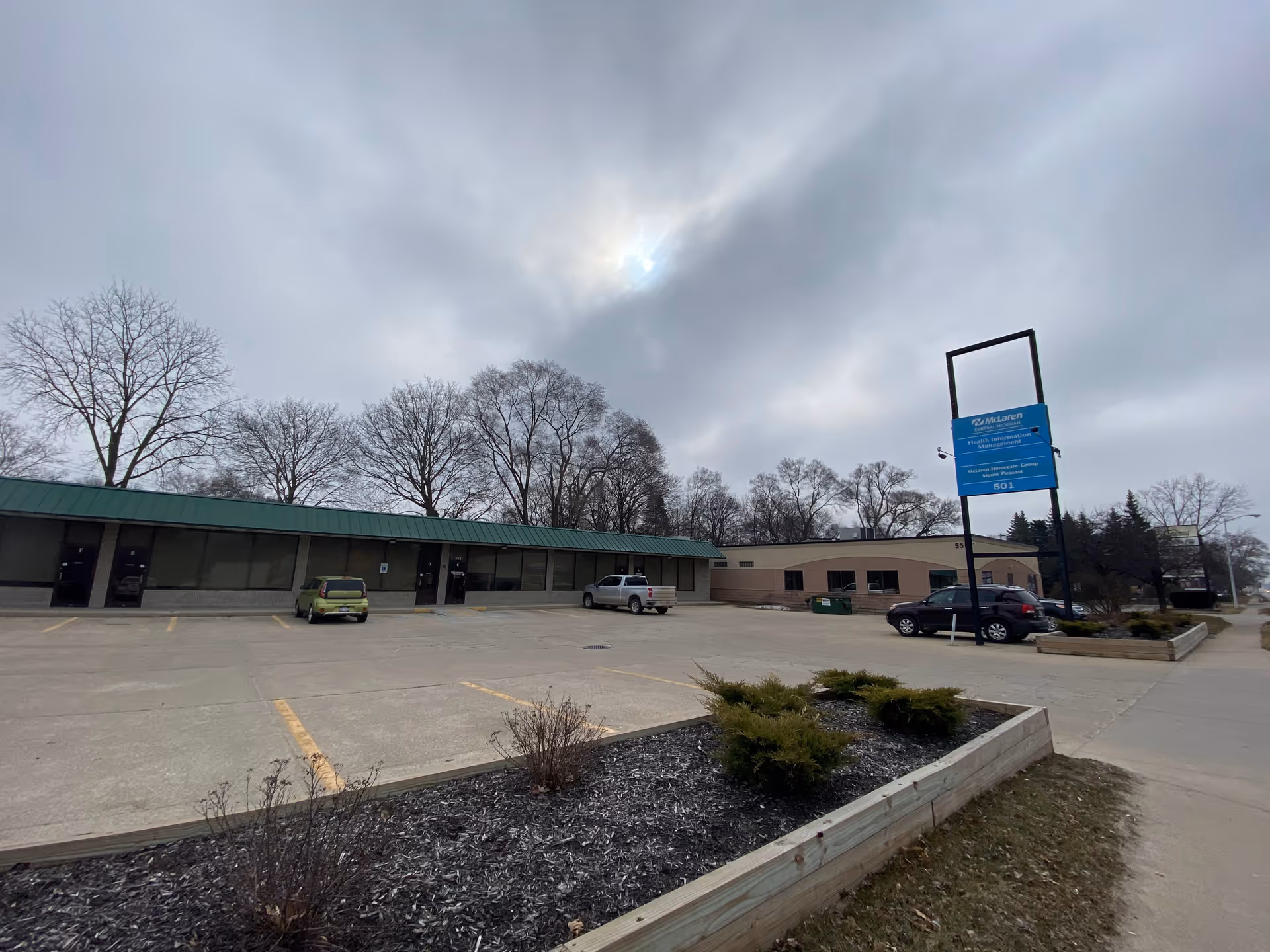 Exterior view of a low, single-story building with a parking lot and blue sign.
