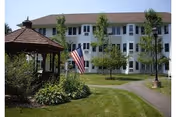 Front exterior view of Rockridge Retirement Community with a gazebo, flag, and green lawn.