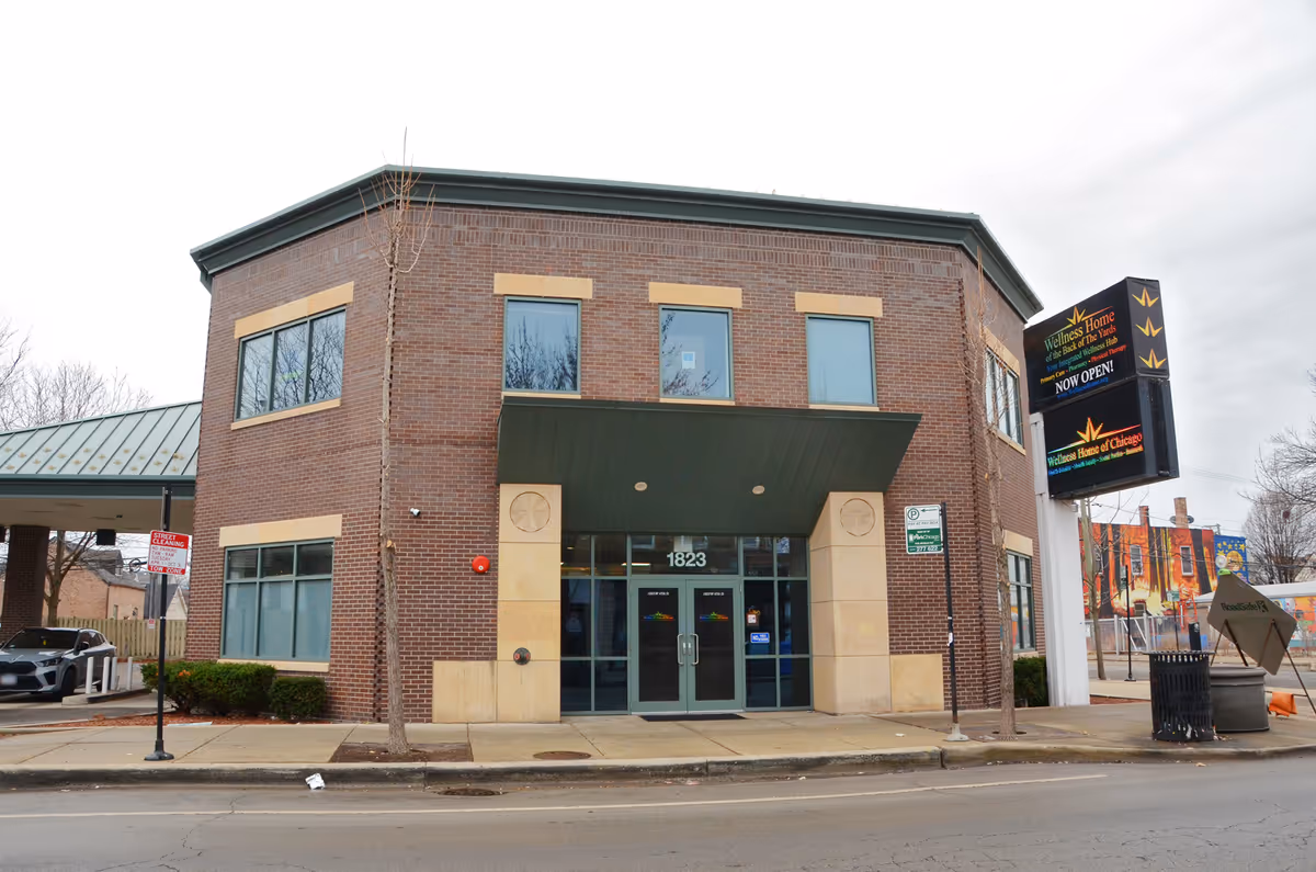 Two-story brick building with glass doors and a green awning on a city street.
