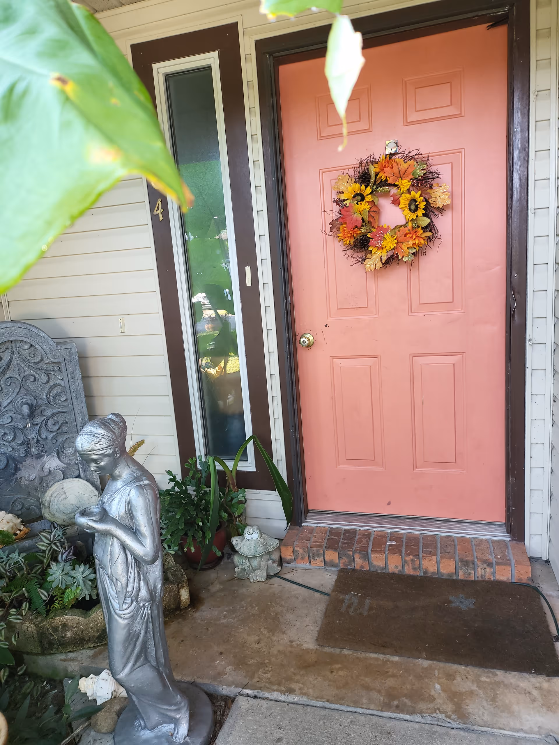 Pink front door with wreath beside window and garden statues at senior living entrance.