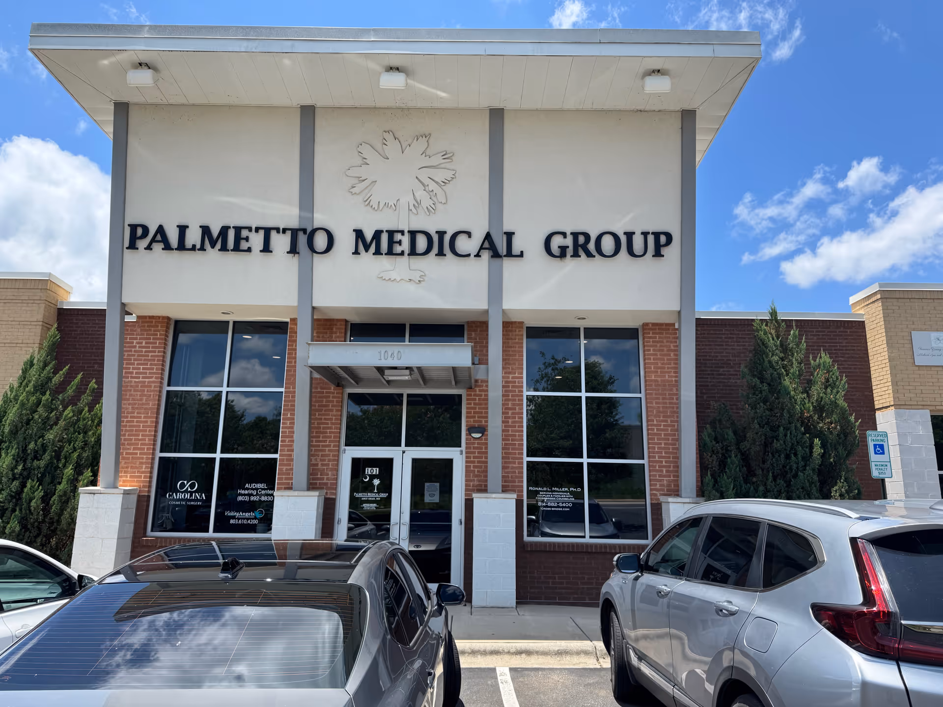 Front view of Palmetto Medical Group building with glass doors and signage; cars parked outside.