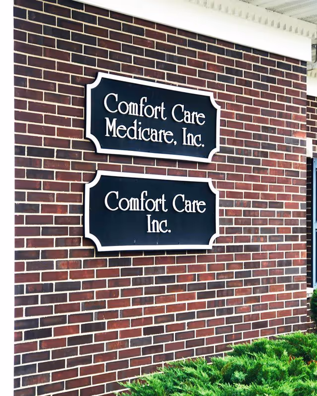 Brick building exterior with two sign plaques reading Comfort Care Medicare, Inc.