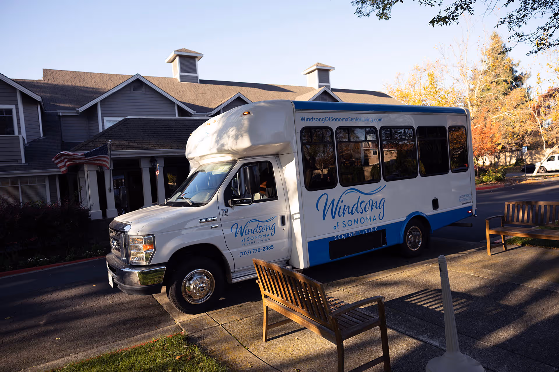 Exterior of Windsong of Sonoma Senior Living with a parked bus and benches.