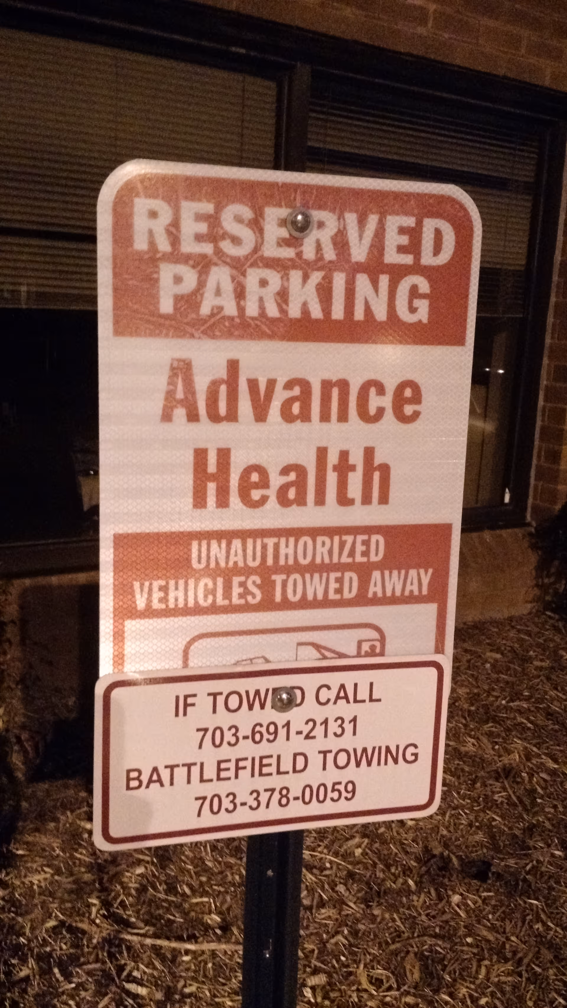 Outdoor parking sign for Advance Health stating reserved parking and towing warnings.